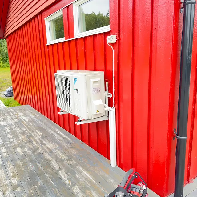 Varmepumpe utedel på rød vegg