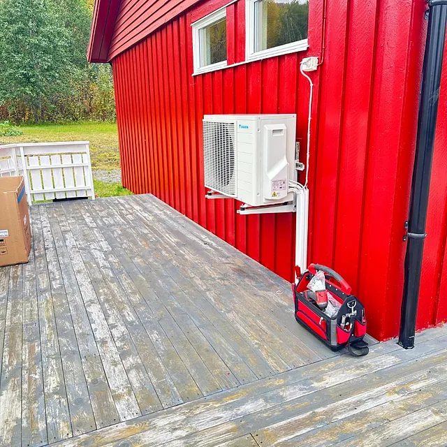 Varmepumpe utedel på rød vegg